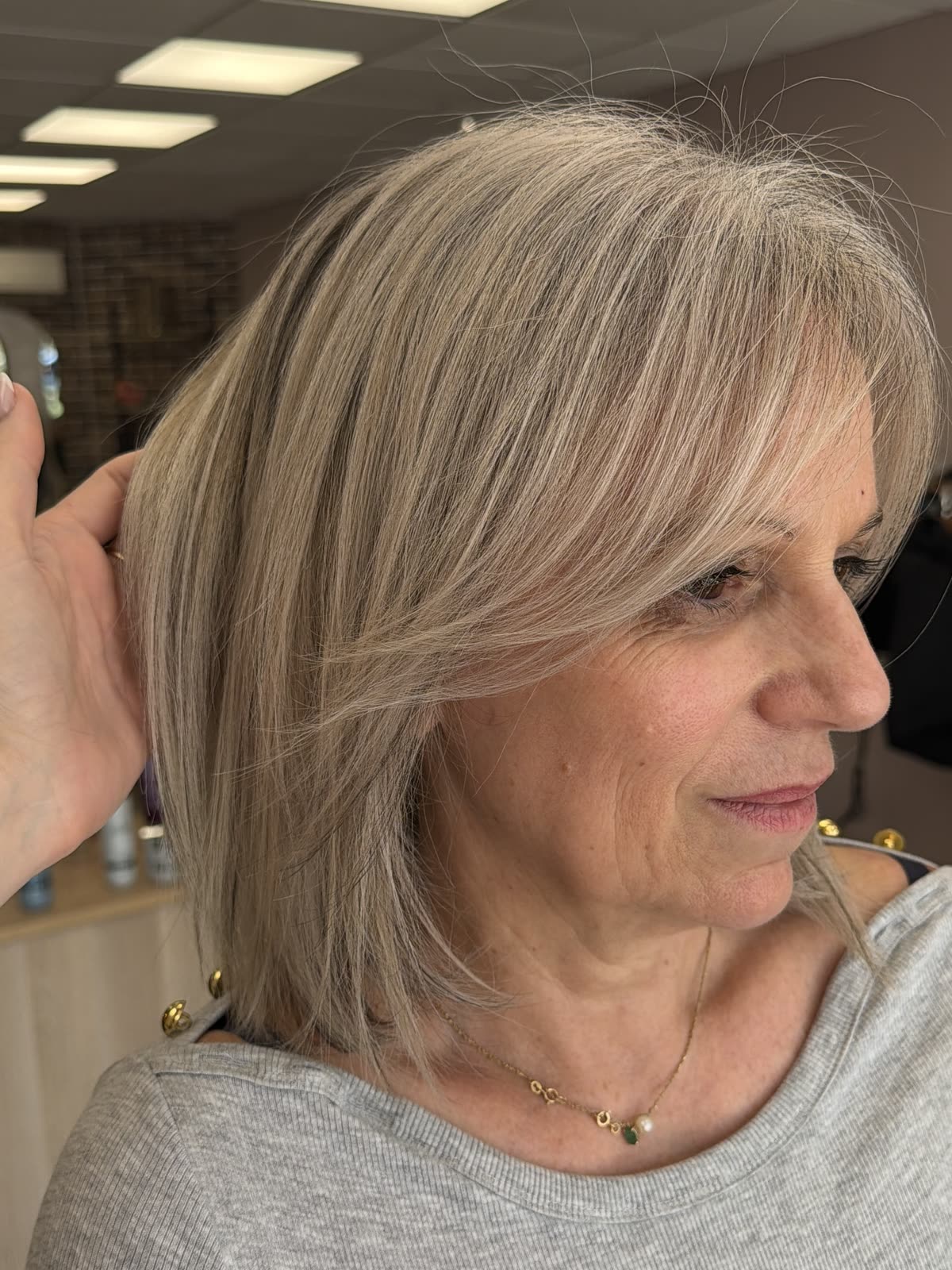 Après le grey balayage : blond clair lumineux où la repousse blanche se fond, sans démarcation — réalisation Valentine Mathieu